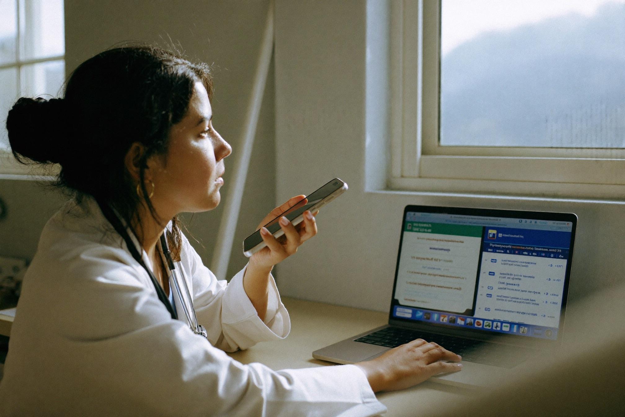 Médica dita uma receita ao celular na mesa do consultório